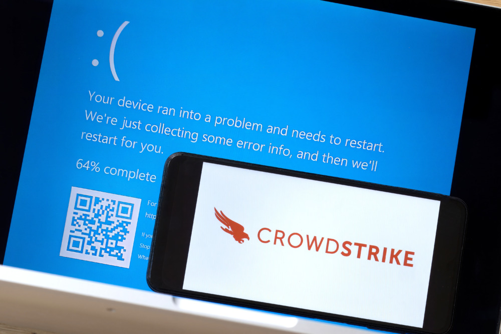 crowdstrike outage shown by phone with crowdstrike logo against Windows blue screen of death